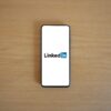 Top view of a smartphone displaying the LinkedIn logo on a wooden surface.